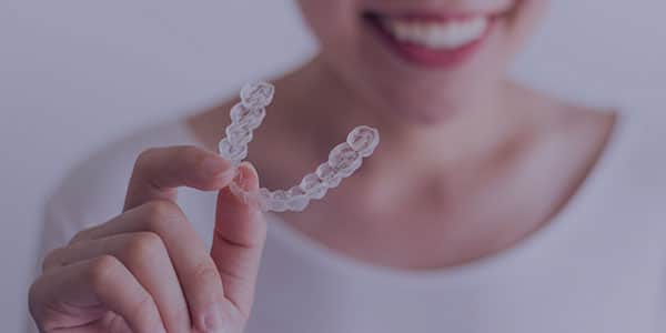 A woman holding an Invisalign tray